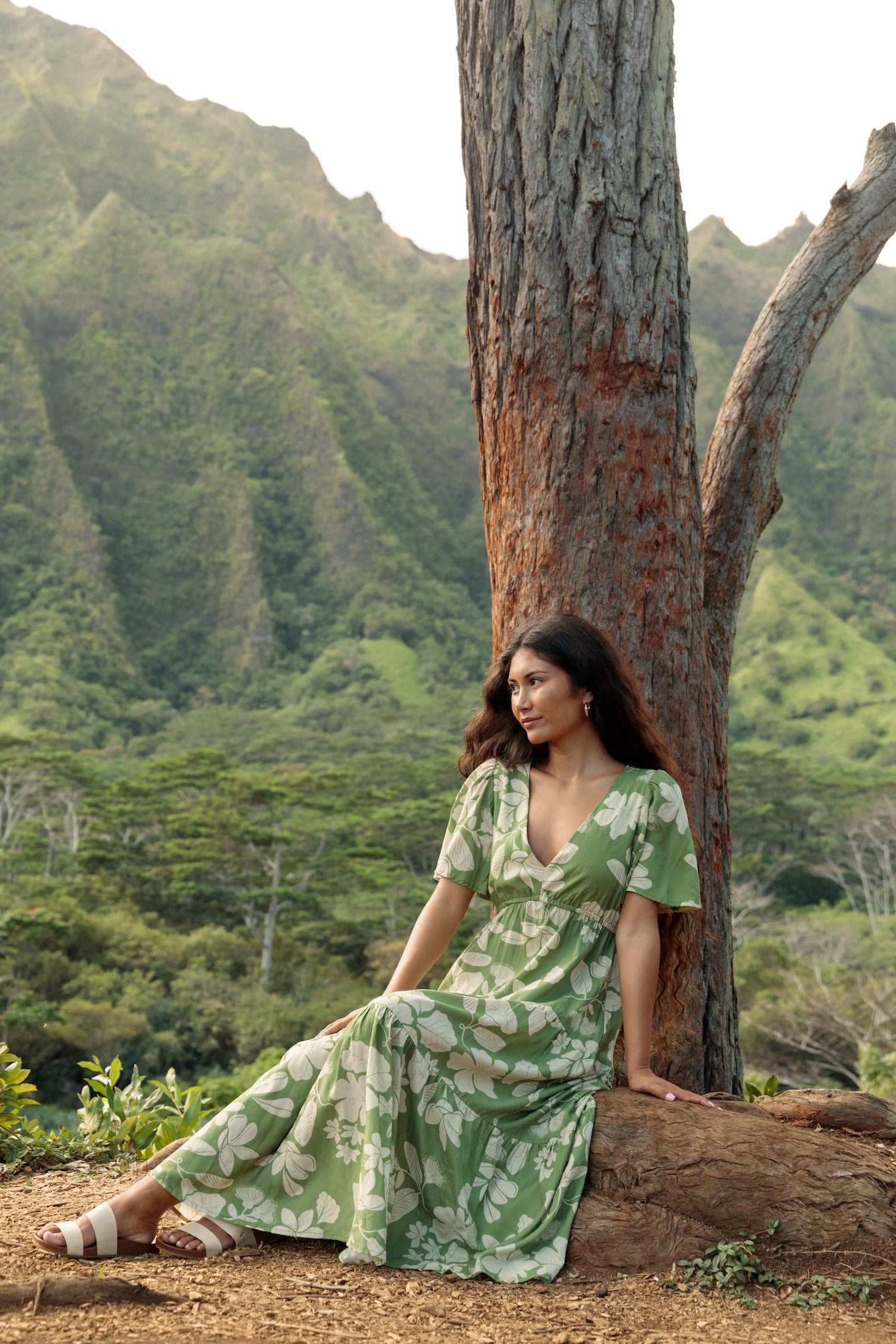 woman with brown hair wearing green v neck maxi dress with native Hawaiian plants 
