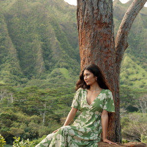 woman with brown hair wearing green v neck maxi dress with native Hawaiian plants 