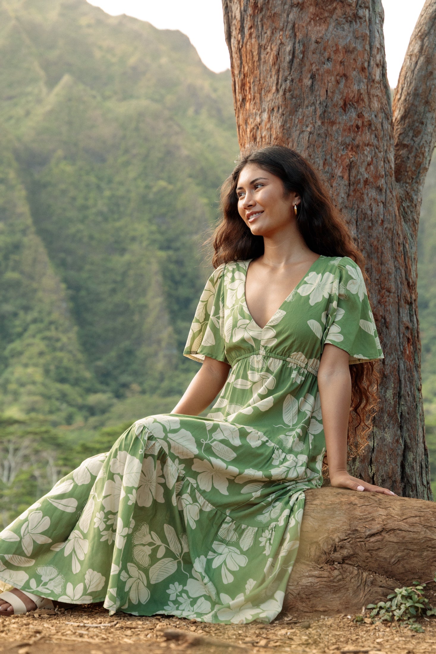 woman with brown hair wearing green v neck maxi dress with native Hawaiian plants 