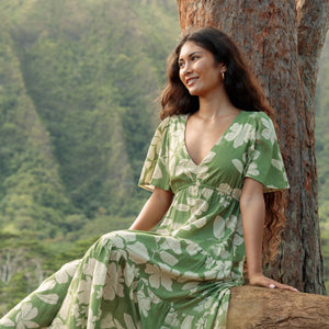 woman with brown hair wearing green v neck maxi dress with native Hawaiian plants 