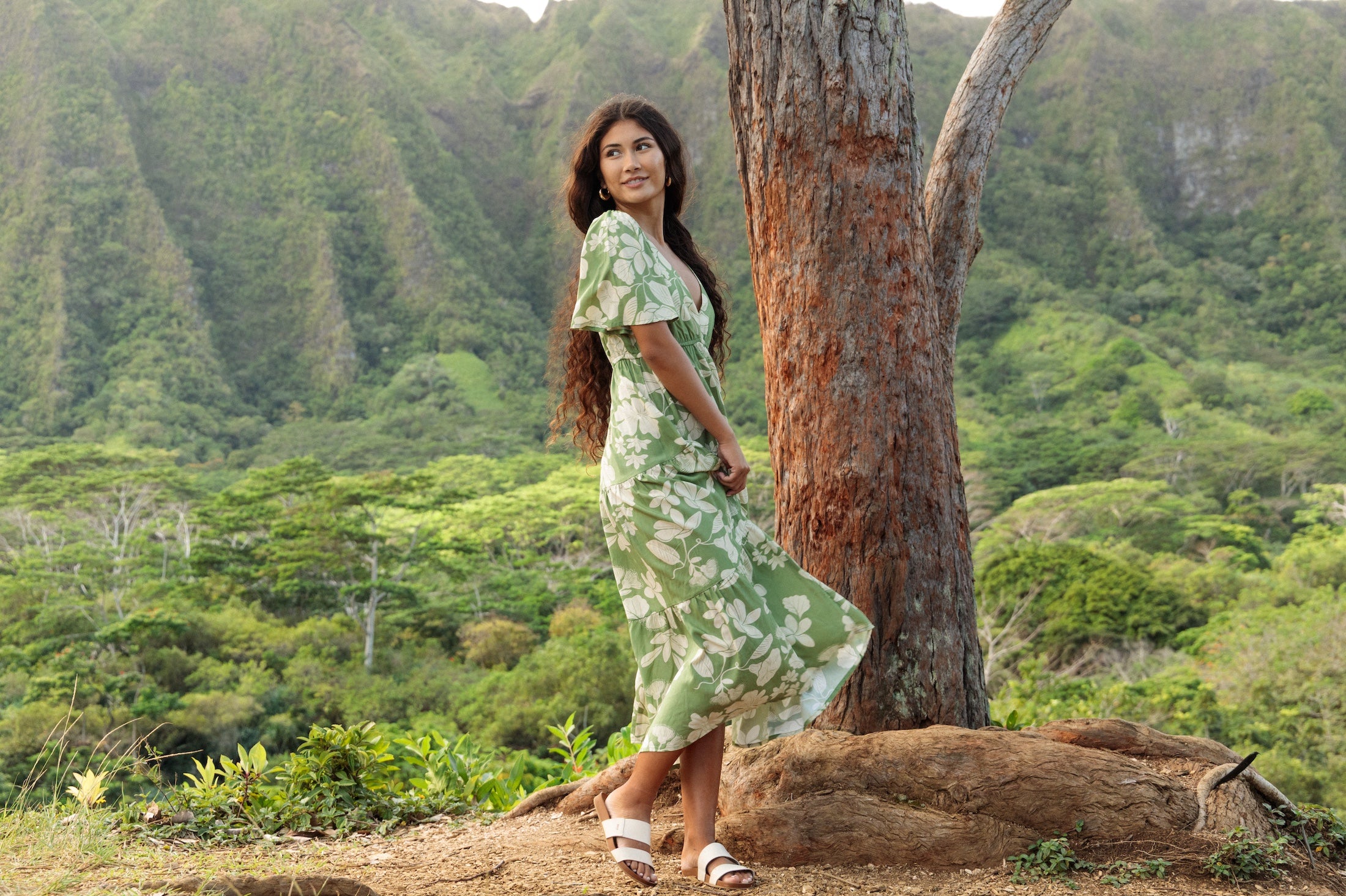 woman with brown hair wearing green v neck maxi dress with native Hawaiian plants 