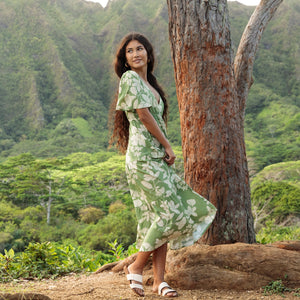woman with brown hair wearing green v neck maxi dress with native Hawaiian plants 