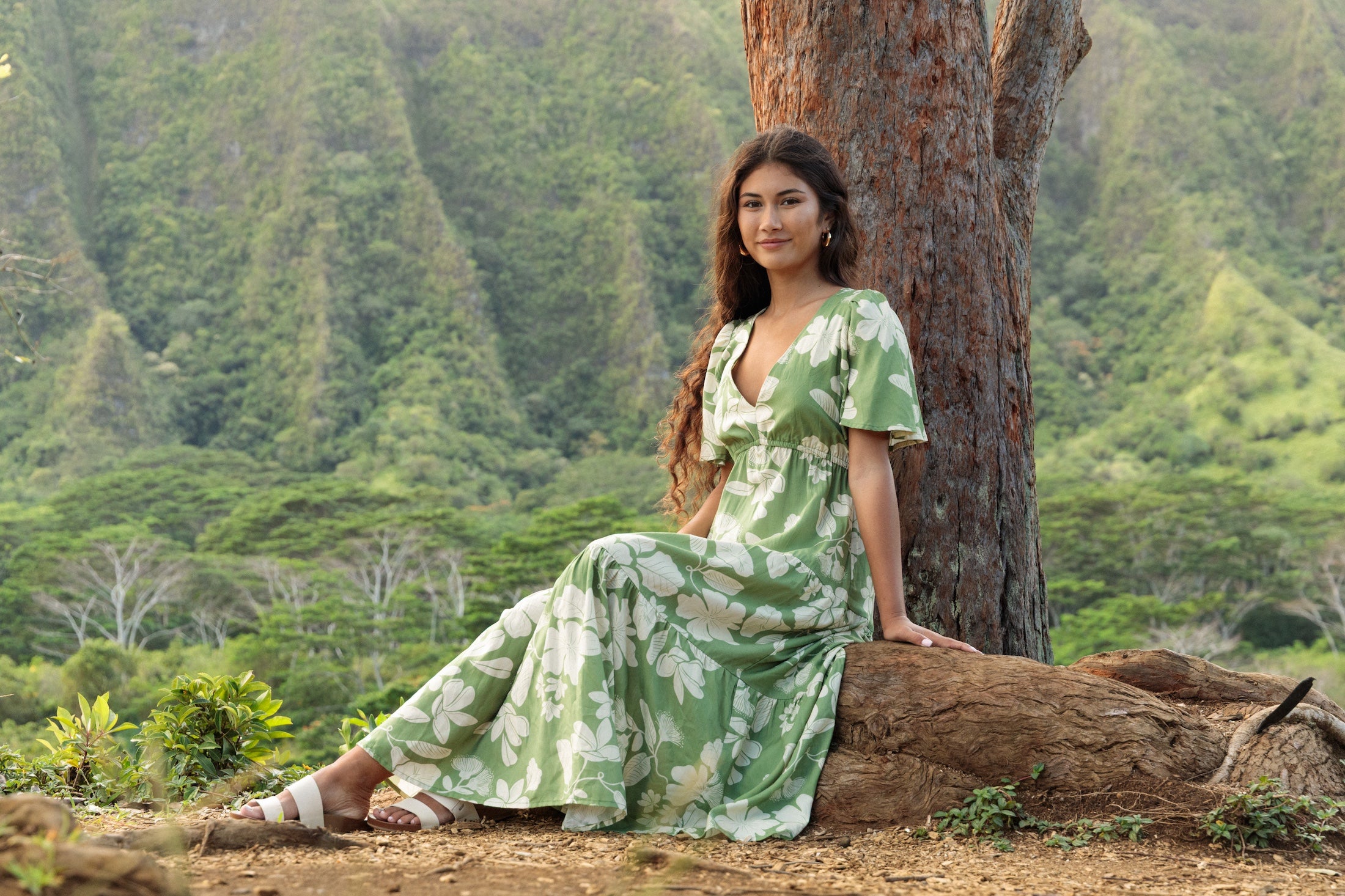 woman with brown hair wearing green v neck maxi dress with native Hawaiian plants 