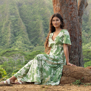 woman with brown hair wearing green v neck maxi dress with native Hawaiian plants 