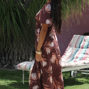 woman wearing brown maxi, v-neck, flutter sleeve dress with protea print