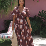 woman wearing brown maxi, v-neck, flutter sleeve dress with protea print