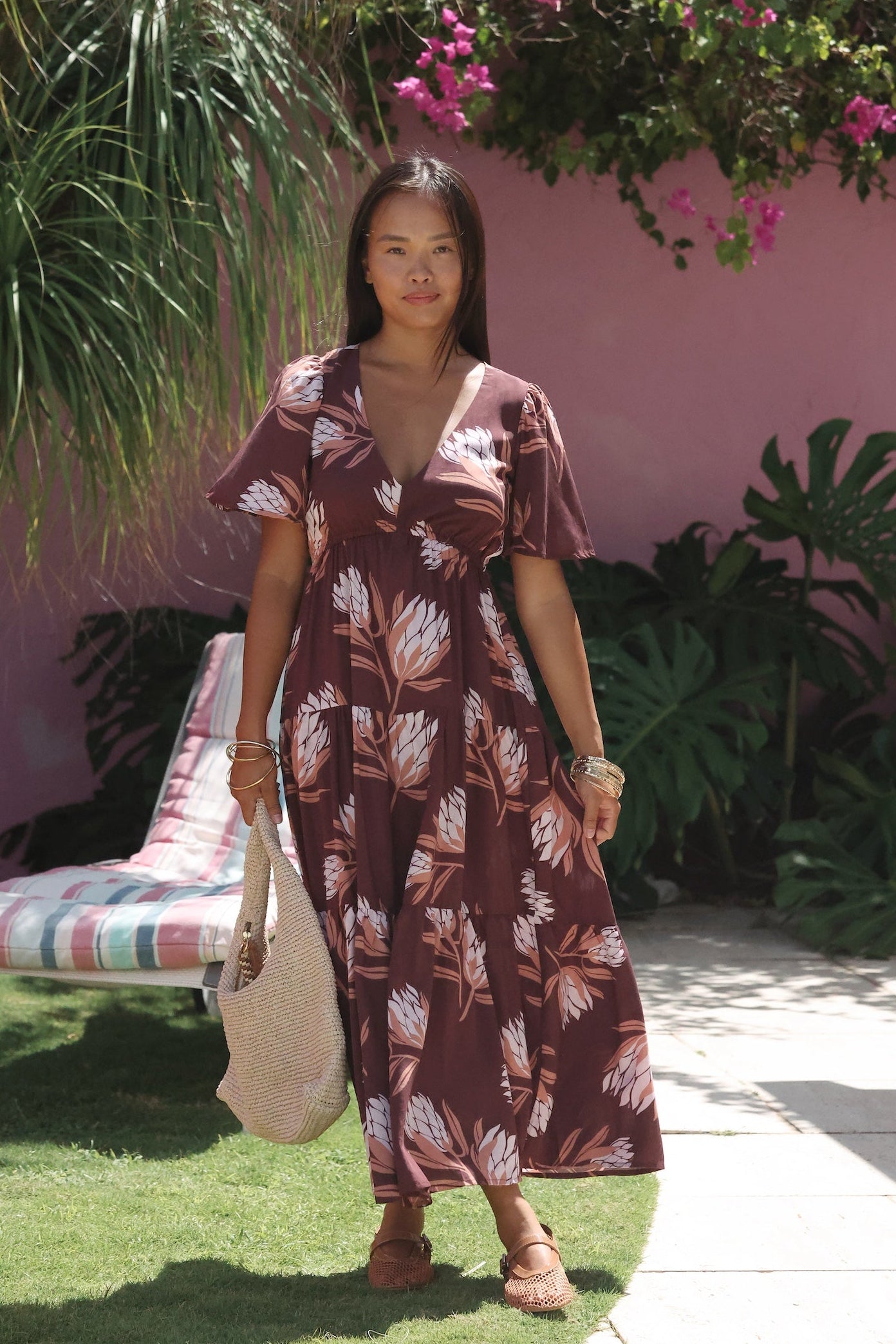 woman wearing brown maxi, v-neck, flutter sleeve dress with protea print