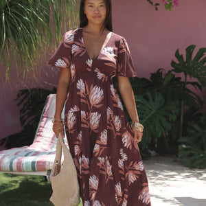 woman wearing brown maxi, v-neck, flutter sleeve dress with protea print