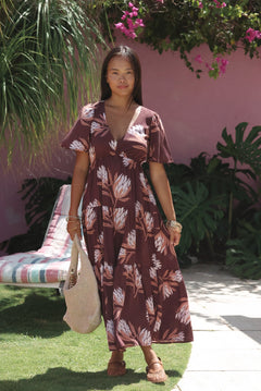 woman wearing brown maxi, v-neck, flutter sleeve dress with protea print