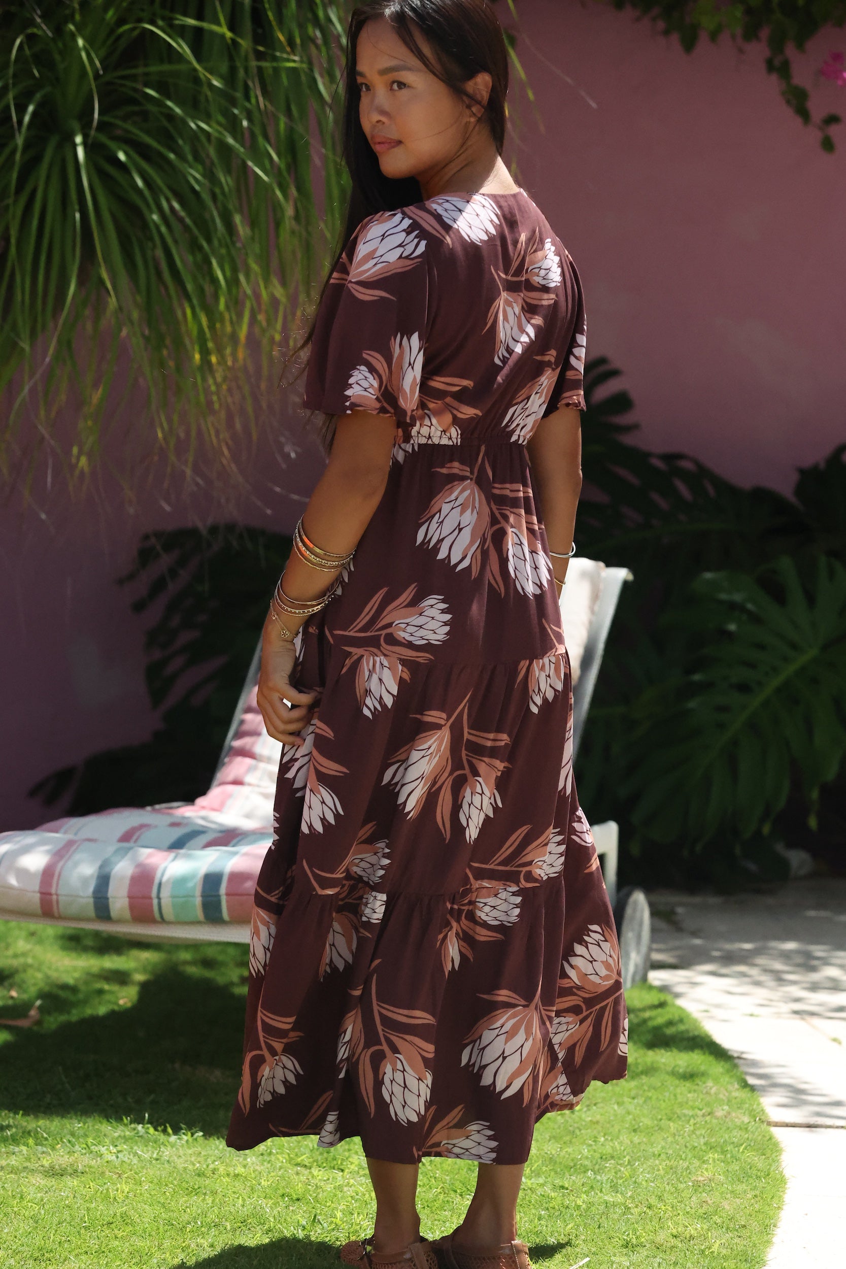 woman wearing brown maxi, v-neck, flutter sleeve dress with protea print