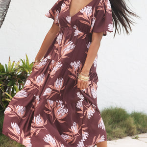 woman wearing brown maxi, v-neck, flutter sleeve dress with protea print