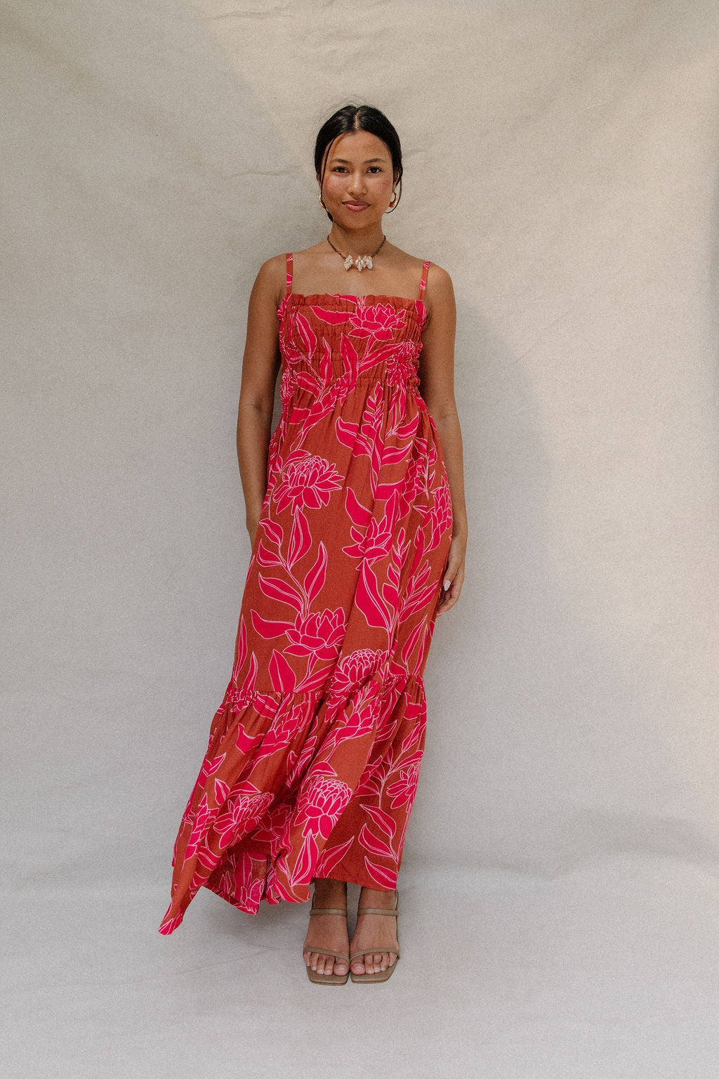woman with brown hair wearing a spaghetti strap maxi dress with awapuhi print