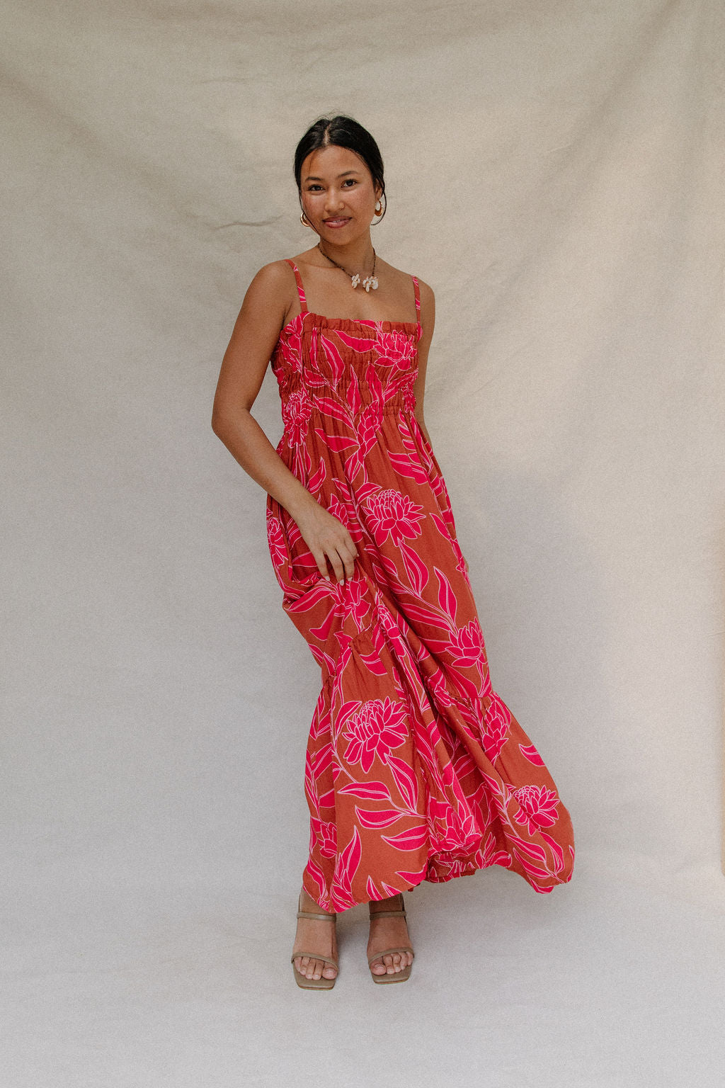 woman with brown hair wearing a spaghetti strap maxi dress with awapuhi print