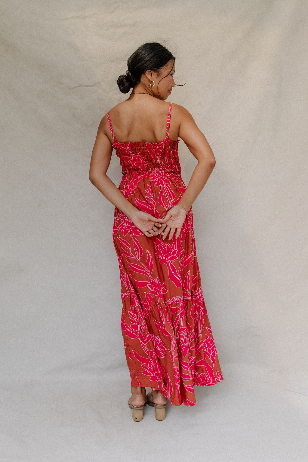 woman with brown hair wearing a spaghetti strap maxi dress with awapuhi print
