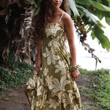 woman with brown hair wearing a maxi flowy dress in a green color with naupaka pattern throughout. 
