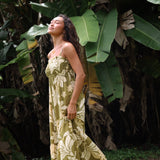 woman with brown hair wearing a maxi flowy dress in a green color with naupaka pattern throughout. 