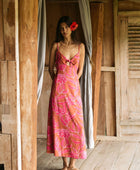 A woman with dark hair wears a YIREH full length dress featuring a knotted, sweetheart neckline. It is the Marina Dress in the Garden 'Awapuhi print. 