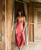 A woman with dark hair wears a YIREH full length dress featuring a knotted, sweetheart neckline. It is the Marina Dress in the Garden 'Awapuhi print. 