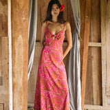 A woman with dark hair wears a YIREH full length dress featuring a knotted, sweetheart neckline. It is the Marina Dress in the Garden 'Awapuhi print. 