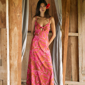 A woman with dark hair wears a YIREH full length dress featuring a knotted, sweetheart neckline. It is the Marina Dress in the Garden 'Awapuhi print. 