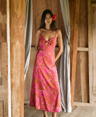 A woman with dark hair wears a YIREH full length dress featuring a knotted, sweetheart neckline. It is the Marina Dress in the Garden 'Awapuhi print. 