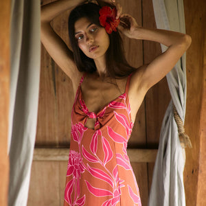 A woman with dark hair wears a YIREH full length dress featuring a knotted, sweetheart neckline. It is the Marina Dress in the Garden 'Awapuhi print. 