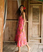 A woman with dark hair wears a YIREH full length dress featuring a knotted, sweetheart neckline. It is the Marina Dress in the Garden 'Awapuhi print. 