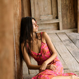 A woman with dark hair wears a YIREH full length dress featuring a knotted, sweetheart neckline. It is the Marina Dress in the Garden 'Awapuhi print. 
