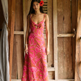 A woman with dark hair wears a YIREH full length dress featuring a knotted, sweetheart neckline. It is the Marina Dress in the Garden 'Awapuhi print. 