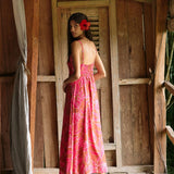 A woman with dark hair wears a YIREH full length dress featuring a knotted, sweetheart neckline. It is the Marina Dress in the Garden 'Awapuhi print. 