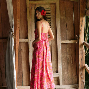 A woman with dark hair wears a YIREH full length dress featuring a knotted, sweetheart neckline. It is the Marina Dress in the Garden 'Awapuhi print. 