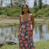 woman with brown hair wearing a navy maxi dress with knot neckline and bright pink hibiscus print