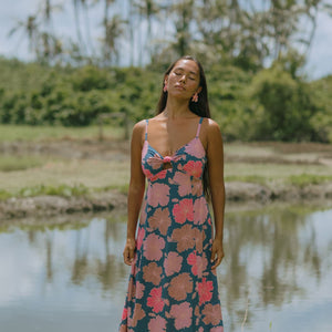 woman with brown hair wearing a navy maxi dress with knot neckline and bright pink hibiscus print