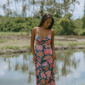 woman with brown hair wearing a navy maxi dress with knot neckline and bright pink hibiscus print