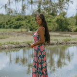 woman with brown hair wearing a navy maxi dress with knot neckline and bright pink hibiscus print