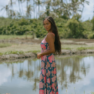 woman with brown hair wearing a navy maxi dress with knot neckline and bright pink hibiscus print