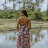 woman with brown hair wearing a navy maxi dress with knot neckline and bright pink hibiscus print