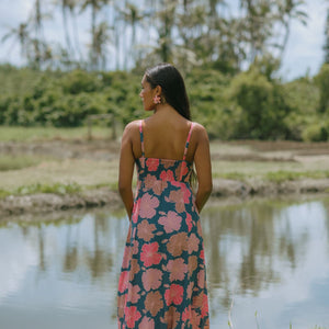 woman with brown hair wearing a navy maxi dress with knot neckline and bright pink hibiscus print
