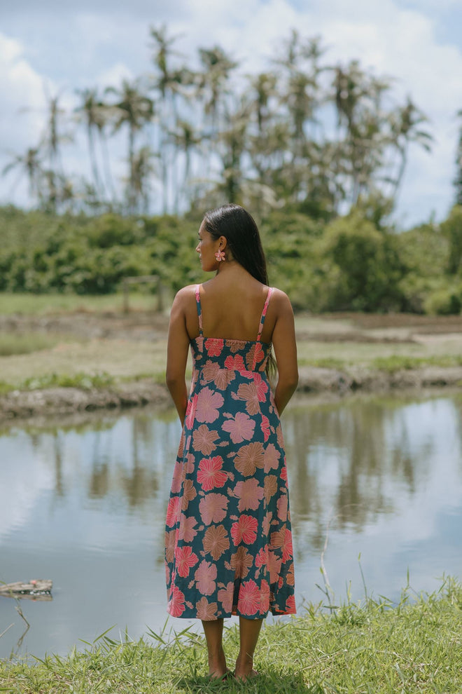 woman with brown hair wearing a navy maxi dress with knot neckline and bright pink hibiscus print