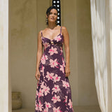 woman with brown hair wearing a dark purple maxi dress with knot tie front and orchid pattern