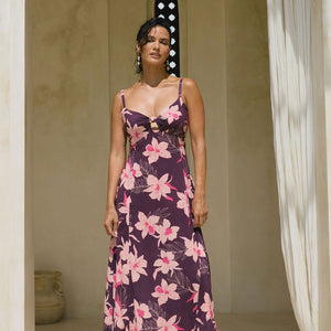 woman with brown hair wearing a dark purple maxi dress with knot tie front and orchid pattern