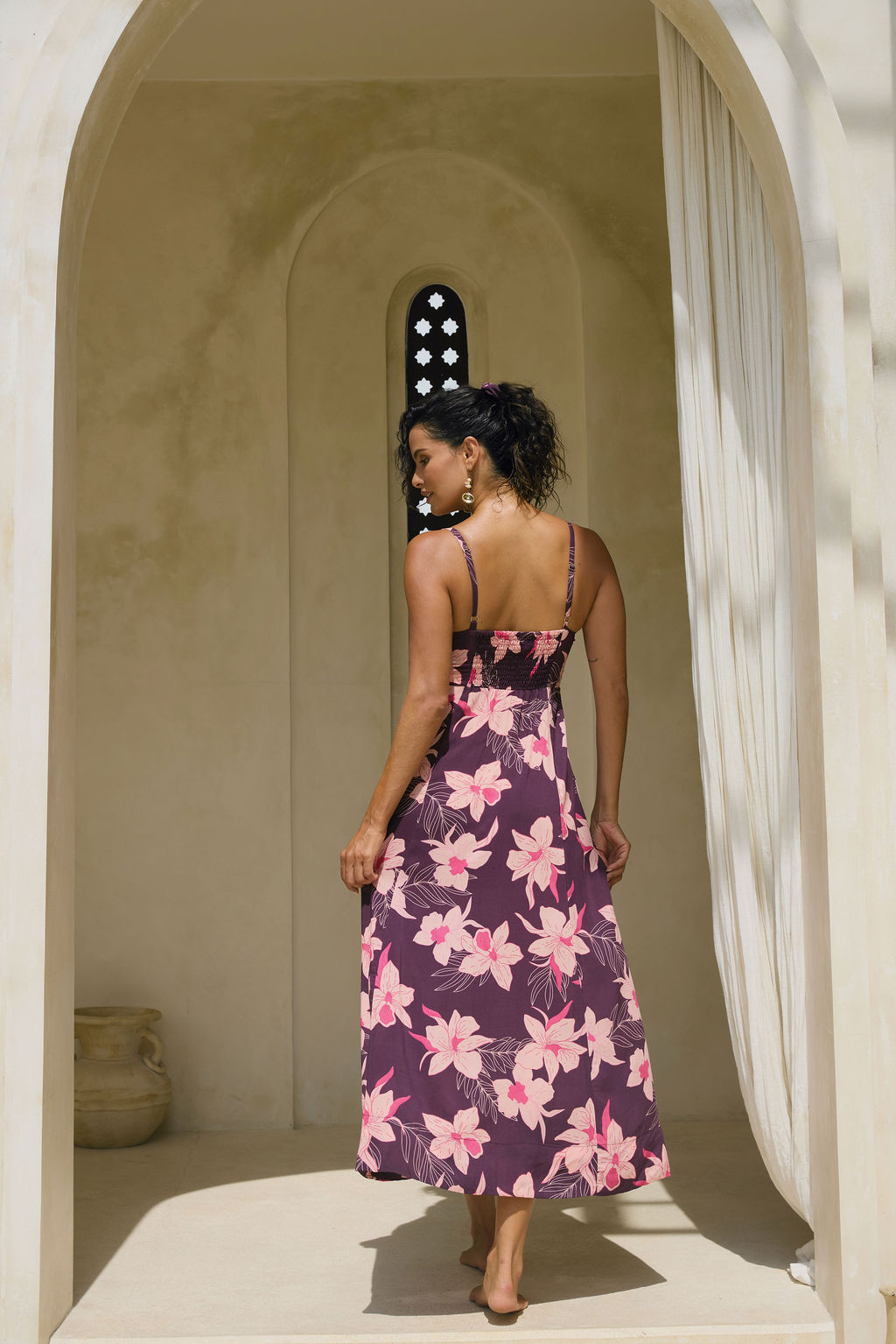 woman with brown hair wearing a dark purple maxi dress with knot tie front and orchid pattern