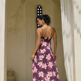 woman with brown hair wearing a dark purple maxi dress with knot tie front and orchid pattern