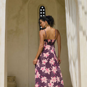 woman with brown hair wearing a dark purple maxi dress with knot tie front and orchid pattern