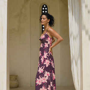 woman with brown hair wearing a dark purple maxi dress with knot tie front and orchid pattern