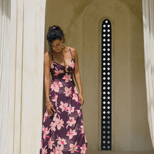woman with brown hair wearing a dark purple maxi dress with knot tie front and orchid pattern
