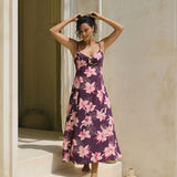 woman with brown hair wearing a dark purple maxi dress with knot tie front and orchid pattern