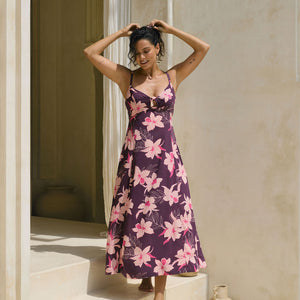 woman with brown hair wearing a dark purple maxi dress with knot tie front and orchid pattern