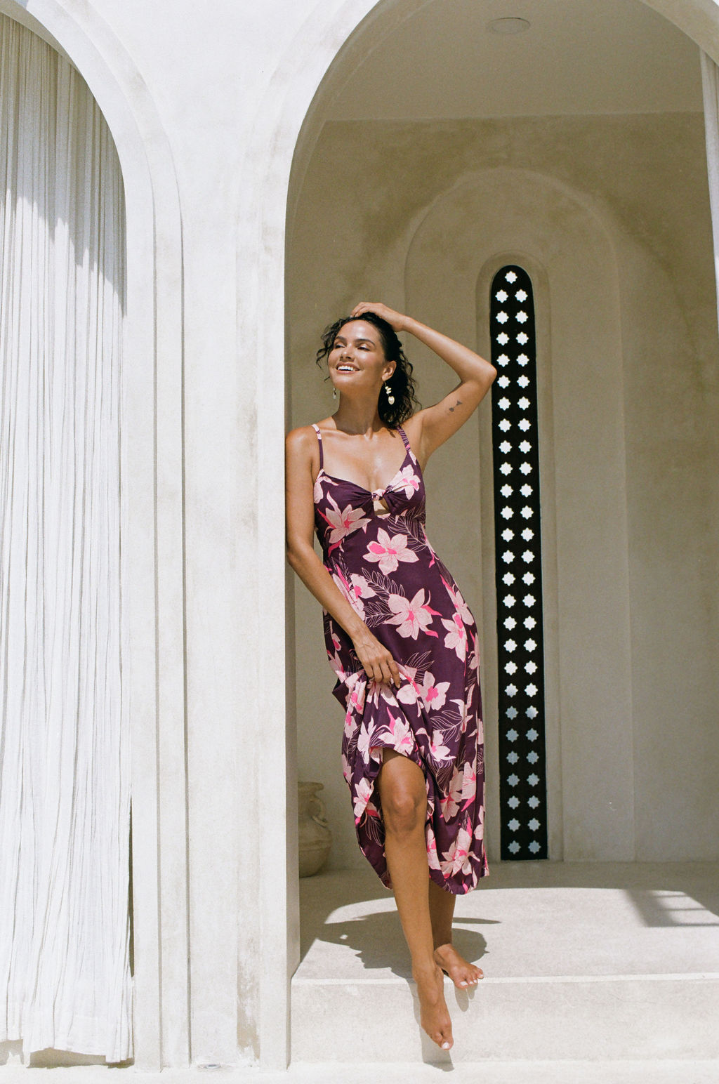 woman with brown hair wearing a dark purple maxi dress with knot tie front and orchid pattern