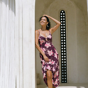 woman with brown hair wearing a dark purple maxi dress with knot tie front and orchid pattern